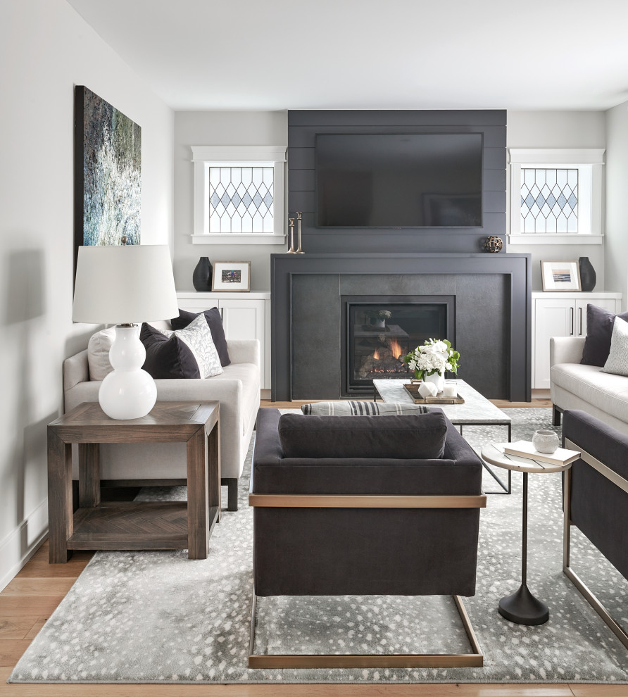 Идея дизайна: открытая гостиная комната в стиле неоклассика (современная классика) с серыми стенами, паркетным полом среднего тона, стандартным камином, телевизором на стене и коричневым полом