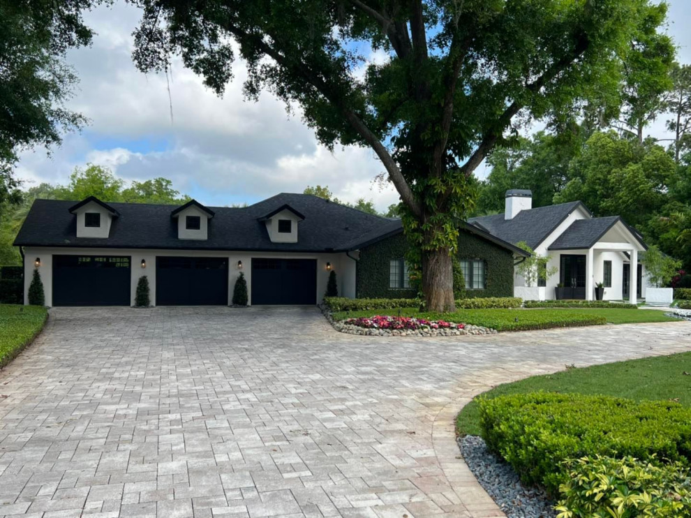 Large mediterranean one-storey stucco white house exterior in Orlando with a gable roof, a shingle roof and a black roof.
