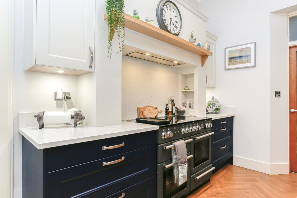 Medium sized traditional l-shaped kitchen/diner in Glasgow with shaker cabinets, blue cabinets, white splashback, an island, white worktops, a single-bowl sink, black appliances and feature lighting.
