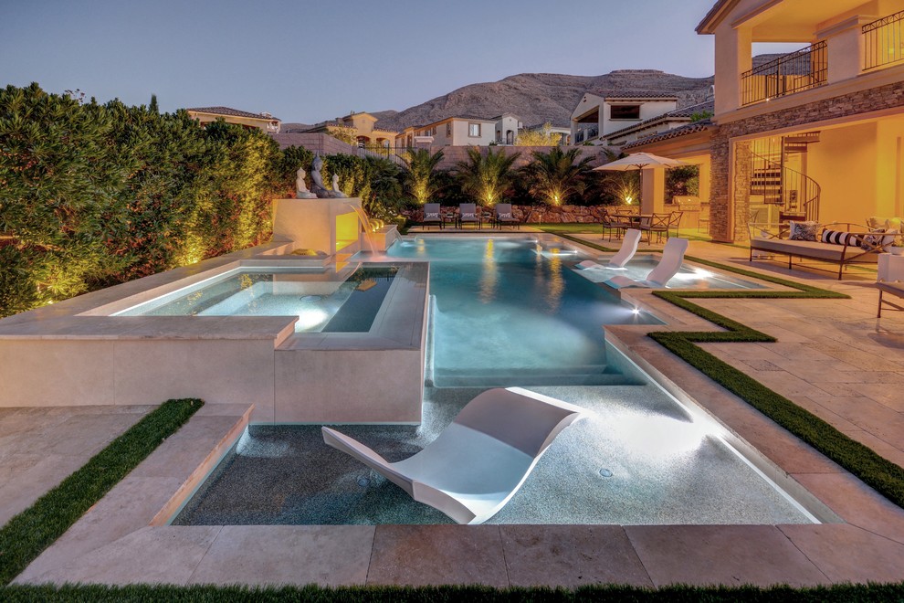 This is an example of a mid-sized modern backyard custom-shaped lap pool in Las Vegas with a hot tub and natural stone pavers.