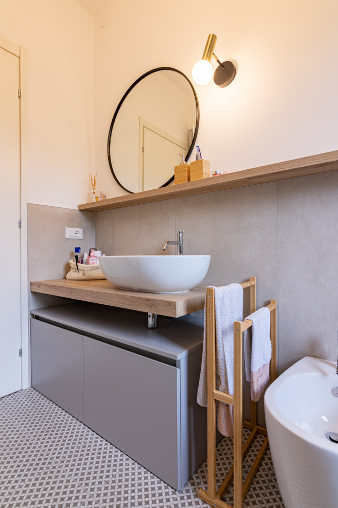 Photo of a medium sized scandinavian shower room bathroom in Other with flat-panel cabinets, grey cabinets, a built-in shower, a two-piece toilet, grey tiles, porcelain tiles, white walls, porcelain flooring, a vessel sink, laminate worktops, grey floors, a sliding door, brown worktops, a laundry area, a single sink and a freestanding vanity unit.
