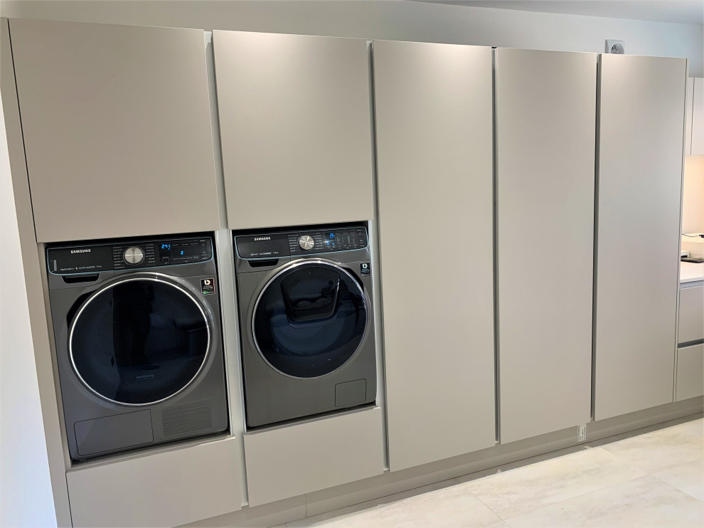 Design ideas for a large traditional single-wall laundry room in Other with an integrated sink, flat-panel cabinets, medium wood cabinets, solid surface benchtops, glass sheet splashback, porcelain floors and white benchtop.