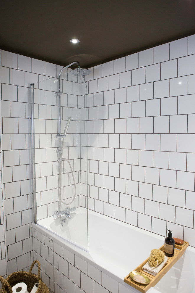 Inspiration for a small modern kids bathroom in London with flat-panel cabinets, a drop-in tub, a shower/bathtub combo, a one-piece toilet, white tile, white walls, terrazzo floors, a console sink, grey floor and a hinged shower door.