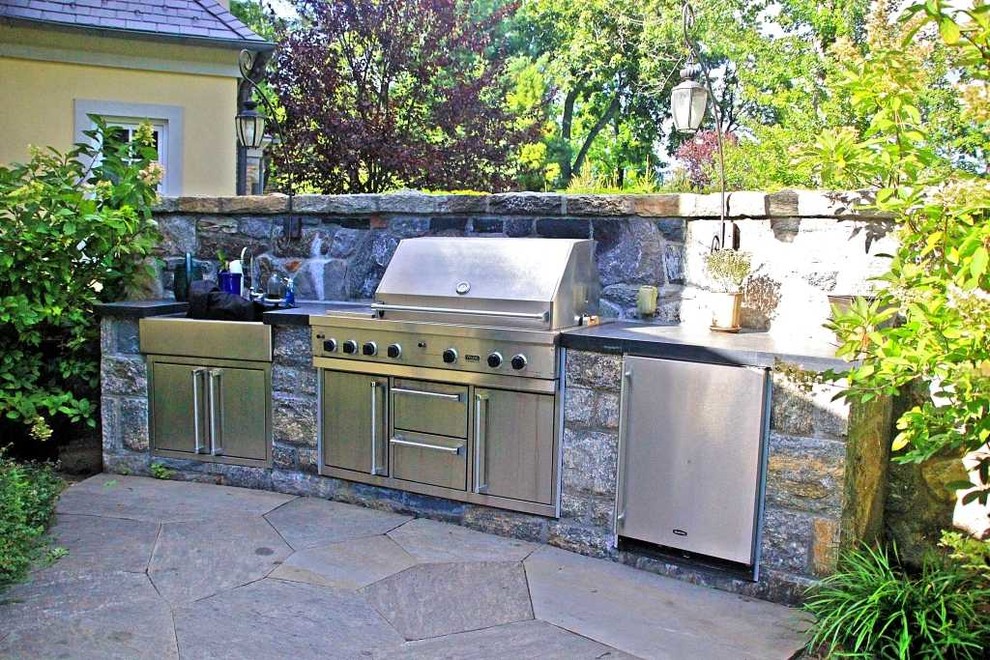 This is an example of a mid-sized arts and crafts backyard patio in New York with an outdoor kitchen, natural stone pavers and no cover.