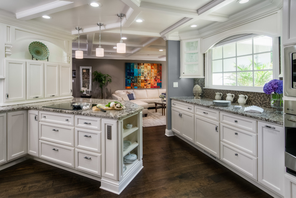Inspiration for a mid-sized traditional u-shaped separate kitchen in San Francisco with recessed-panel cabinets, white cabinets, multi-coloured splashback, mosaic tile splashback, stainless steel appliances, dark hardwood floors, a peninsula, granite benchtops and brown floor.