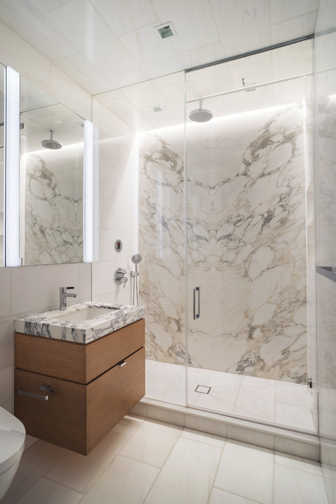 Design ideas for a contemporary bathroom in New York with flat-panel cabinets, medium wood cabinets, an alcove shower, white tile, an undermount sink, white floor, a hinged shower door and white benchtops.