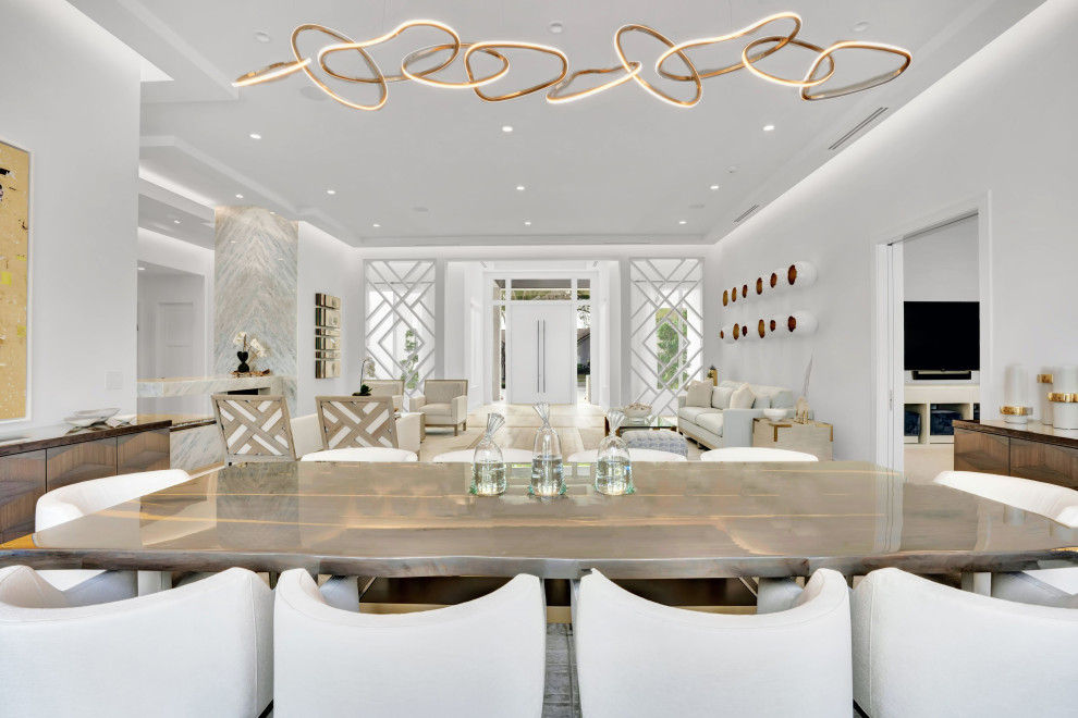 Inspiration for a large contemporary kitchen/dining combo in Miami with beige walls, medium hardwood floors, a two-sided fireplace, a stone fireplace surround, beige floor and recessed.