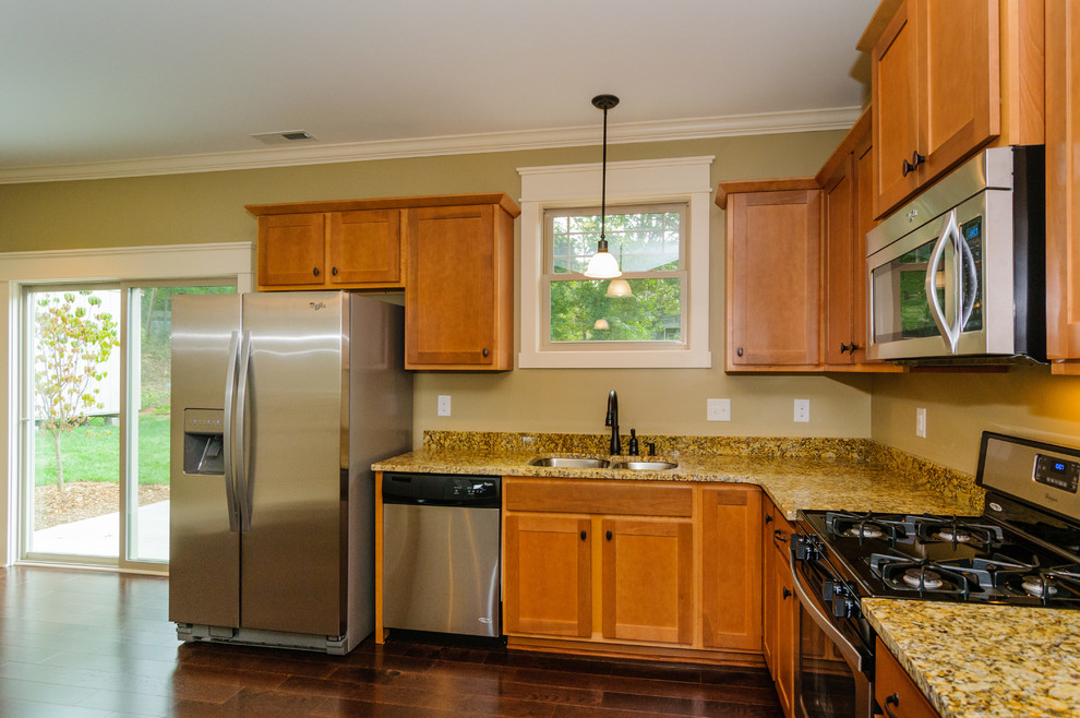 Large transitional u-shaped dark wood floor eat-in kitchen photo with a double-bowl sink, raised-panel cabinets, light wood cabinets, granite countertops, beige backsplash, stainless steel appliances and no island