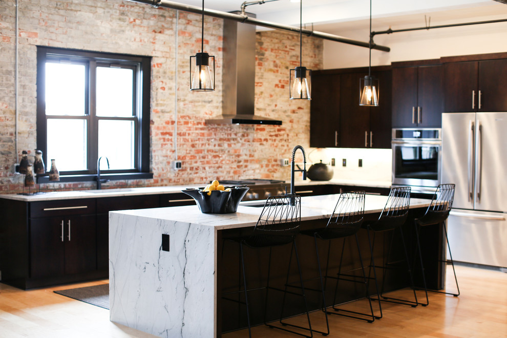 Inspiration for a large industrial l-shaped open plan kitchen in Other with an undermount sink, flat-panel cabinets, dark wood cabinets, marble benchtops, red splashback, brick splashback, stainless steel appliances, light hardwood floors, with island, beige floor and white benchtop.