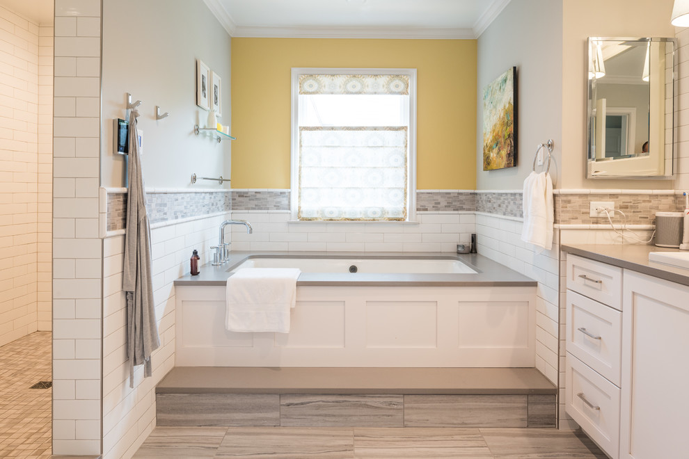 Mid-sized traditional master bathroom in St Louis with shaker cabinets, white cabinets, a hot tub, a double shower, a two-piece toilet, white tile, subway tile, yellow walls, ceramic floors, a trough sink, engineered quartz benchtops, grey floor and a hinged shower door.