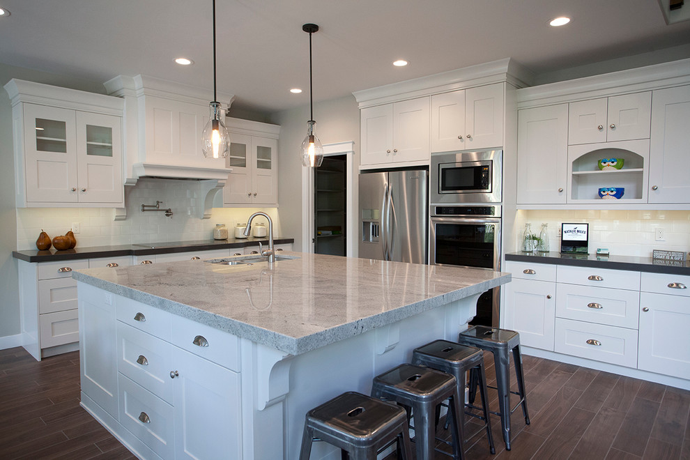 This is an example of a mid-sized arts and crafts u-shaped kitchen in Salt Lake City with a double-bowl sink, shaker cabinets, white cabinets, granite benchtops, white splashback, subway tile splashback, stainless steel appliances and with island.