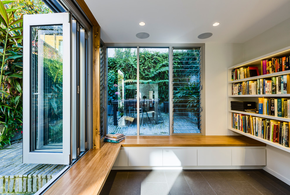 This is an example of a mid-sized contemporary open concept living room in Sydney with a library, white walls, ceramic floors and grey floor.