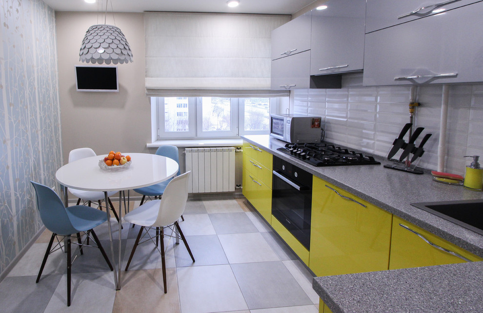 This is an example of a mid-sized contemporary l-shaped separate kitchen in Moscow with yellow cabinets, no island, a drop-in sink, flat-panel cabinets, white splashback, subway tile splashback and black appliances.