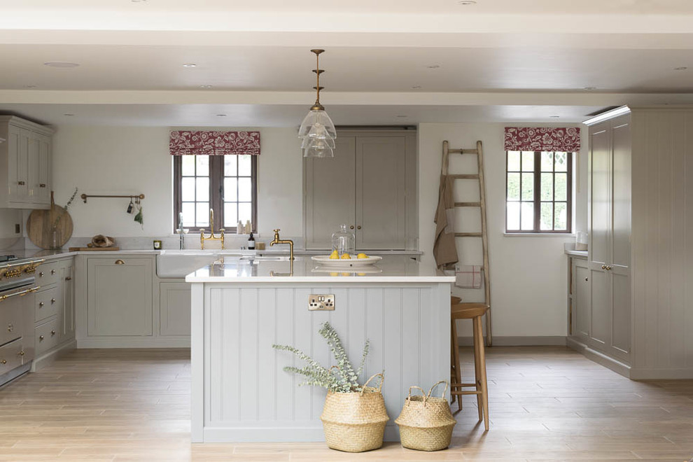 Photo of an expansive country l-shaped eat-in kitchen in Other with a farmhouse sink, shaker cabinets, grey cabinets, quartzite benchtops, white splashback, coloured appliances, porcelain floors, with island and brown floor.