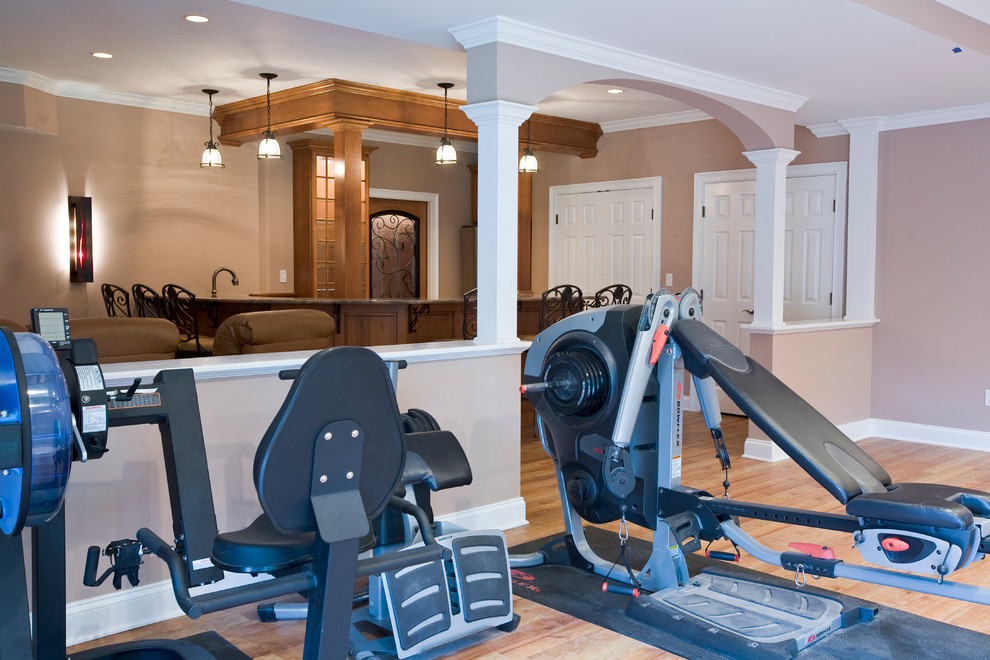 Large country home weight room in Bridgeport with beige walls and light hardwood floors.