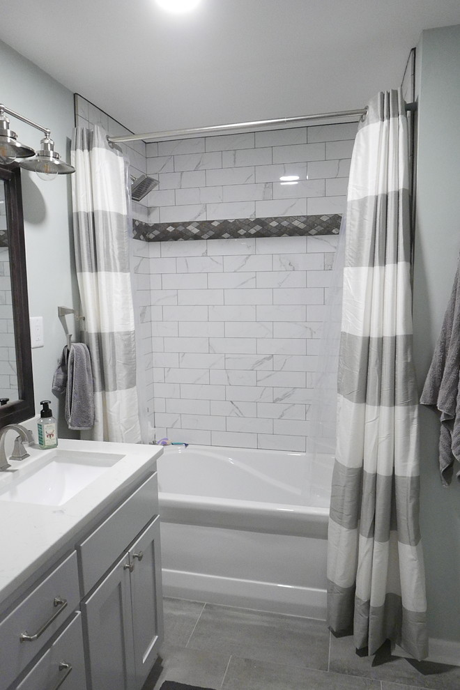 Mid-sized transitional kids bathroom in Other with shaker cabinets, grey cabinets, an alcove tub, a shower/bathtub combo, a two-piece toilet, white tile, porcelain tile, green walls, porcelain floors, an undermount sink, engineered quartz benchtops, grey floor, a shower curtain and white benchtops.