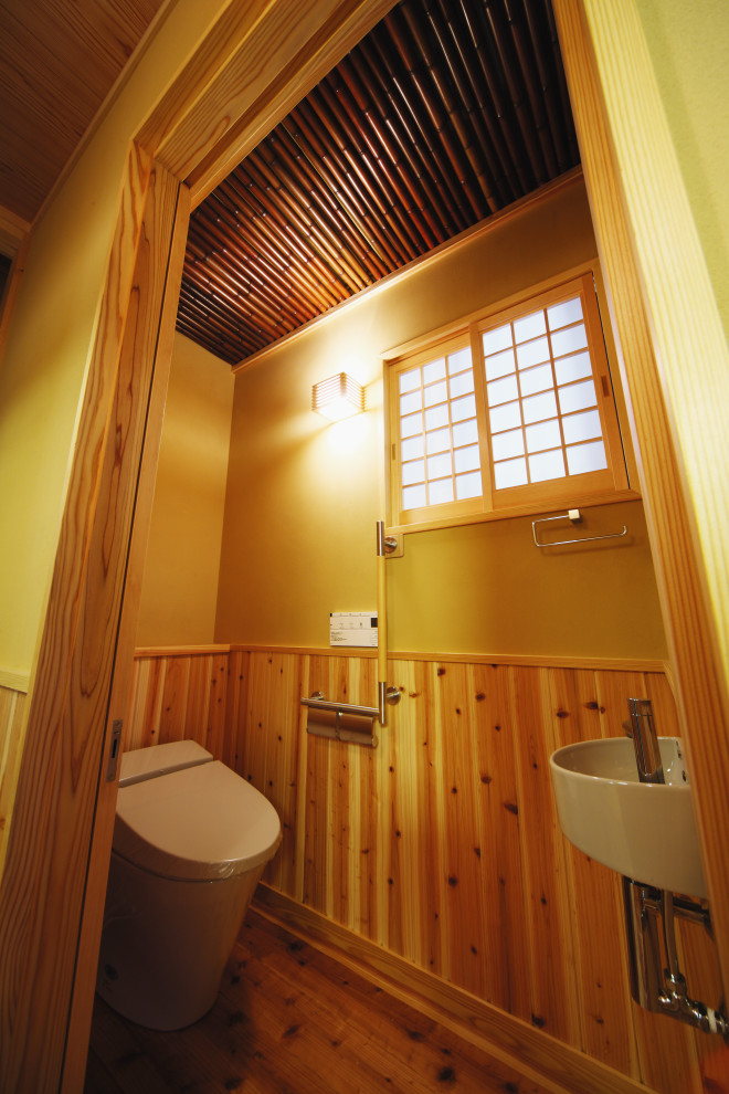 Example of a small asian light wood floor, beige floor and wood wall powder room design in Other with a one-piece toilet