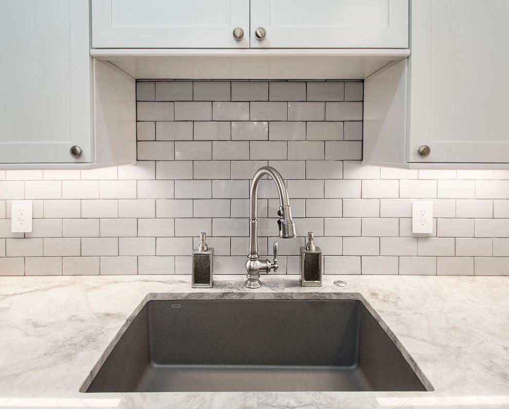Example of a large transitional u-shaped medium tone wood floor open concept kitchen design in Dallas with an undermount sink, shaker cabinets, white cabinets, quartz countertops, white backsplash, porcelain backsplash, stainless steel appliances and an island