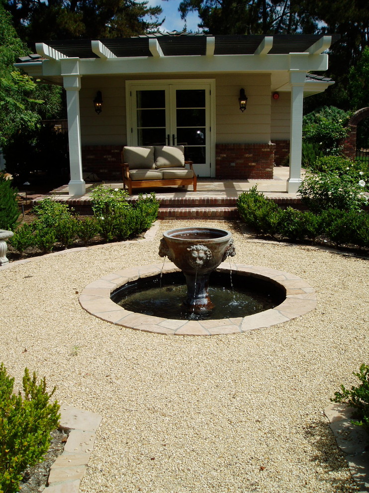 This is an example of a traditional backyard garden in San Diego with a water feature and gravel.