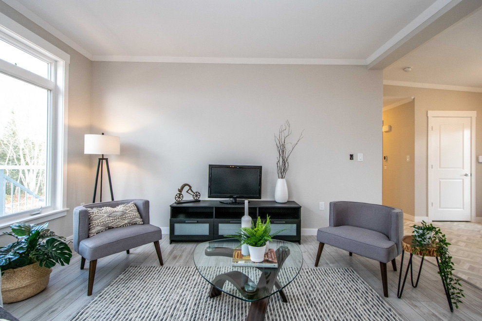 Diseño de sala de estar abierta y abovedada costera de tamaño medio sin chimenea con paredes beige, suelo laminado, televisor independiente y suelo gris