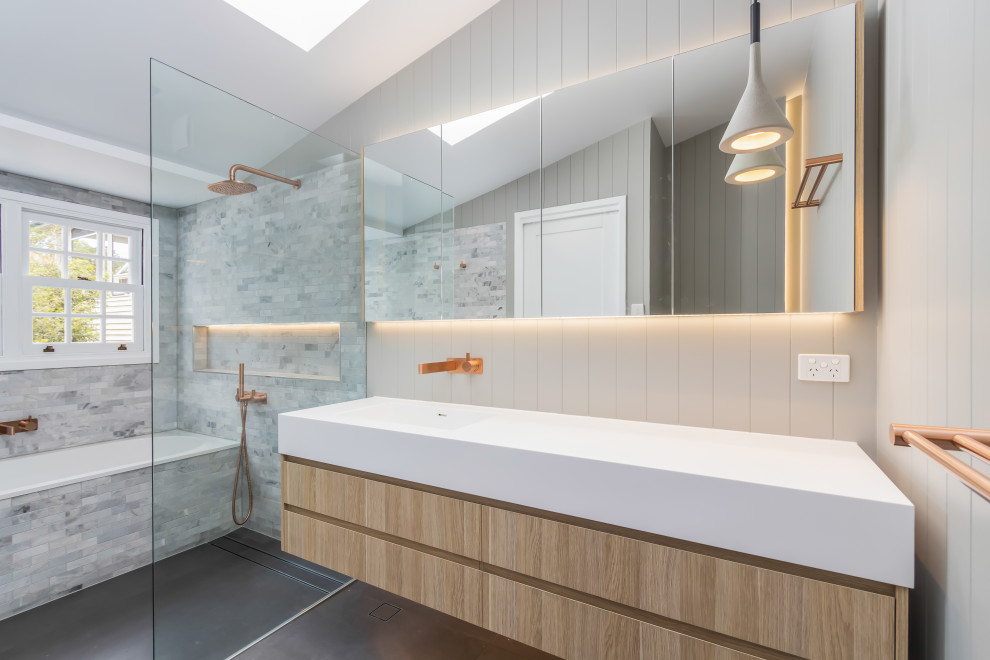 Inspiration for a mid-sized contemporary master wet room bathroom in Brisbane with furniture-like cabinets, light wood cabinets, a drop-in tub, a one-piece toilet, subway tile, porcelain floors, an integrated sink, solid surface benchtops, grey floor, an open shower and white benchtops.