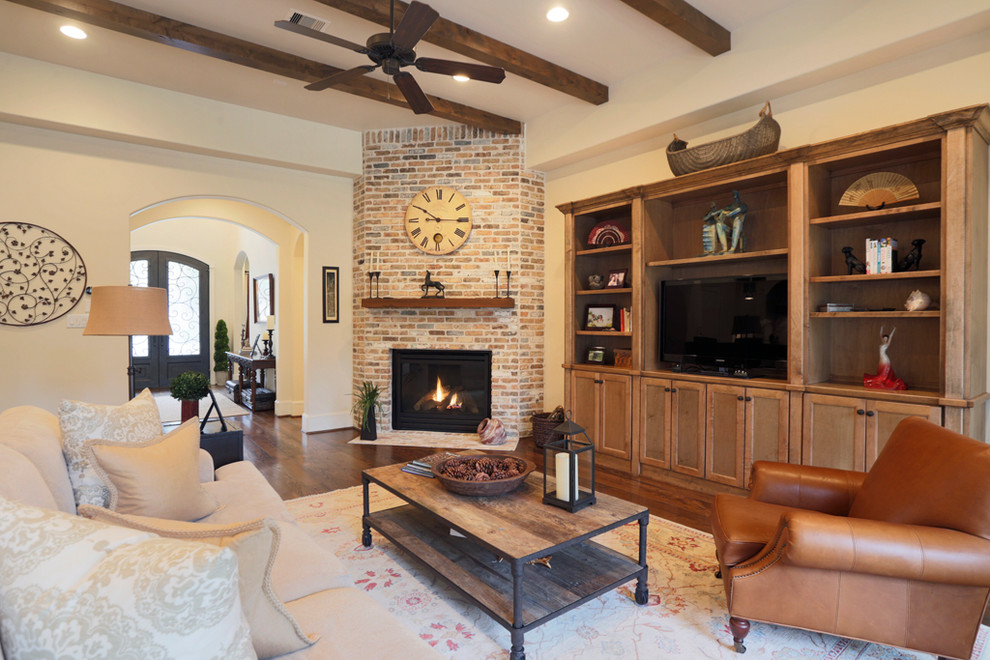 Inspiration for a large transitional open concept family room in Houston with dark hardwood floors, a corner fireplace, a brick fireplace surround, a built-in media wall, beige walls and brown floor.
