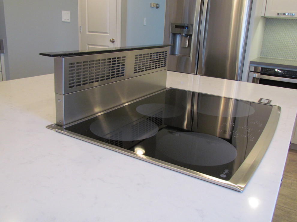 Example of a transitional l-shaped porcelain tile eat-in kitchen design in Chicago with a farmhouse sink, shaker cabinets, white cabinets, quartz countertops, blue backsplash, glass tile backsplash, stainless steel appliances and an island