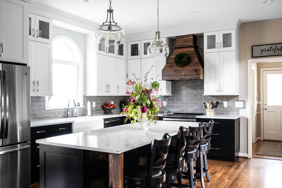 Inspiration for a mid-sized country l-shaped separate kitchen in Charlotte with a farmhouse sink, shaker cabinets, quartz benchtops, grey splashback, subway tile splashback, stainless steel appliances, medium hardwood floors, with island, brown floor, white benchtop and white cabinets.