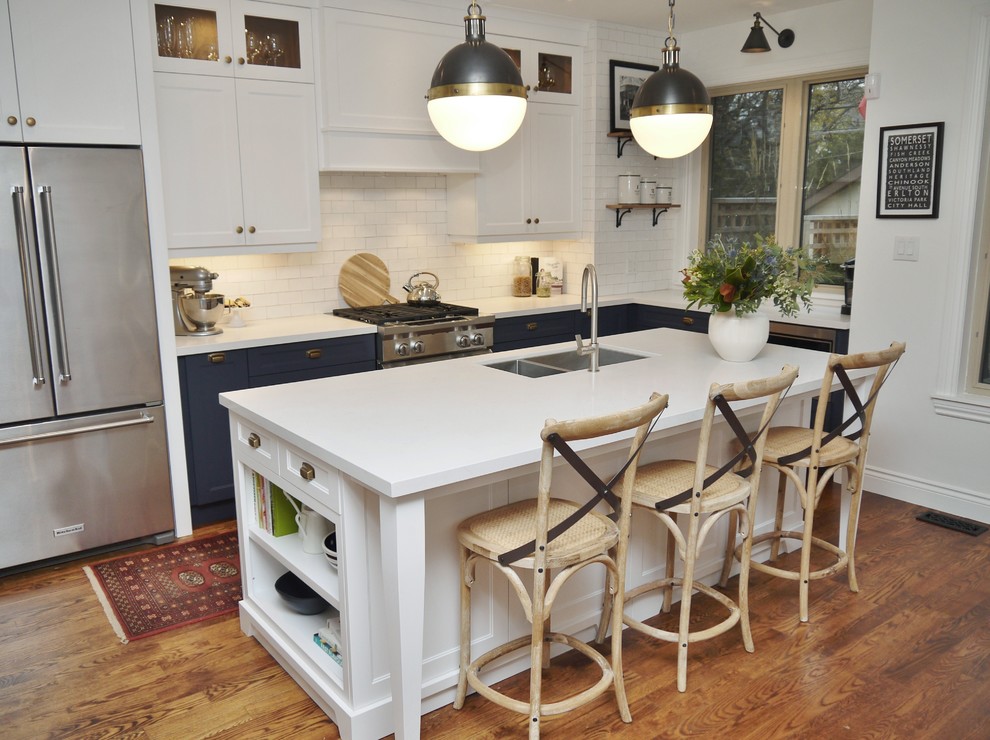 Eat-in kitchen - mid-sized transitional l-shaped medium tone wood floor and brown floor eat-in kitchen idea in Toronto with an undermount sink, shaker cabinets, blue cabinets, quartz countertops, white backsplash, subway tile backsplash, stainless steel appliances, an island and white countertops