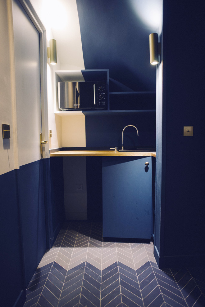 Inspiration for a small transitional l-shaped open plan kitchen in Paris with an undermount sink, blue cabinets, wood benchtops, blue splashback, ceramic splashback, black appliances and ceramic floors.