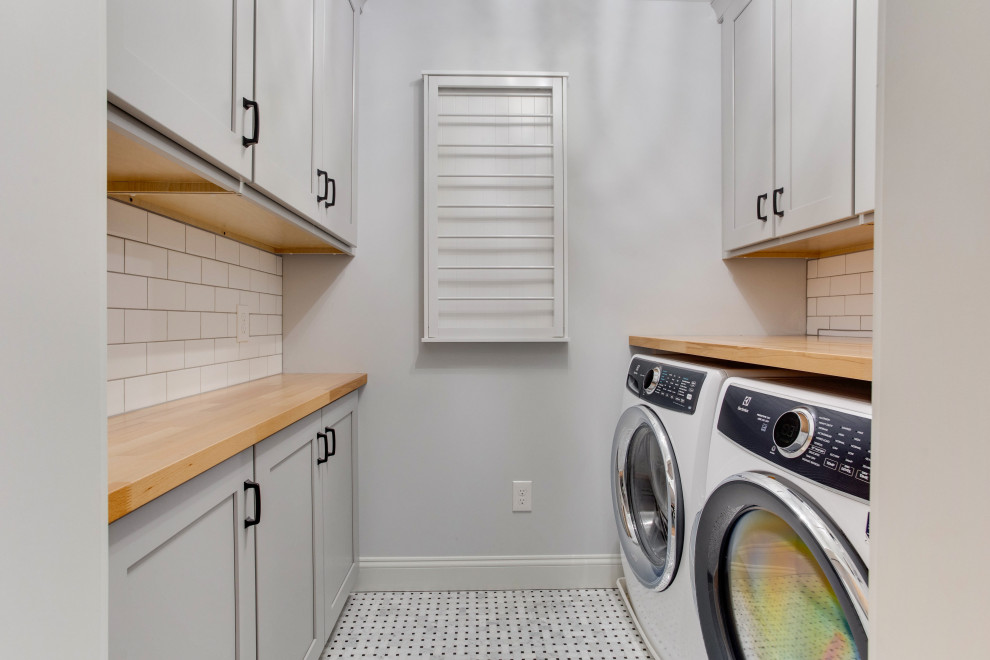 This is an example of a small beach style galley laundry room in Baltimore with recessed-panel cabinets, wood benchtops, white splashback, subway tile splashback and a side-by-side washer and dryer.