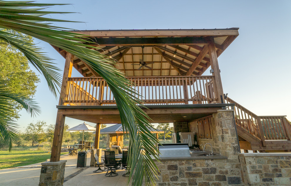 Large mountain style backyard stone patio fountain photo in Austin with a gazebo