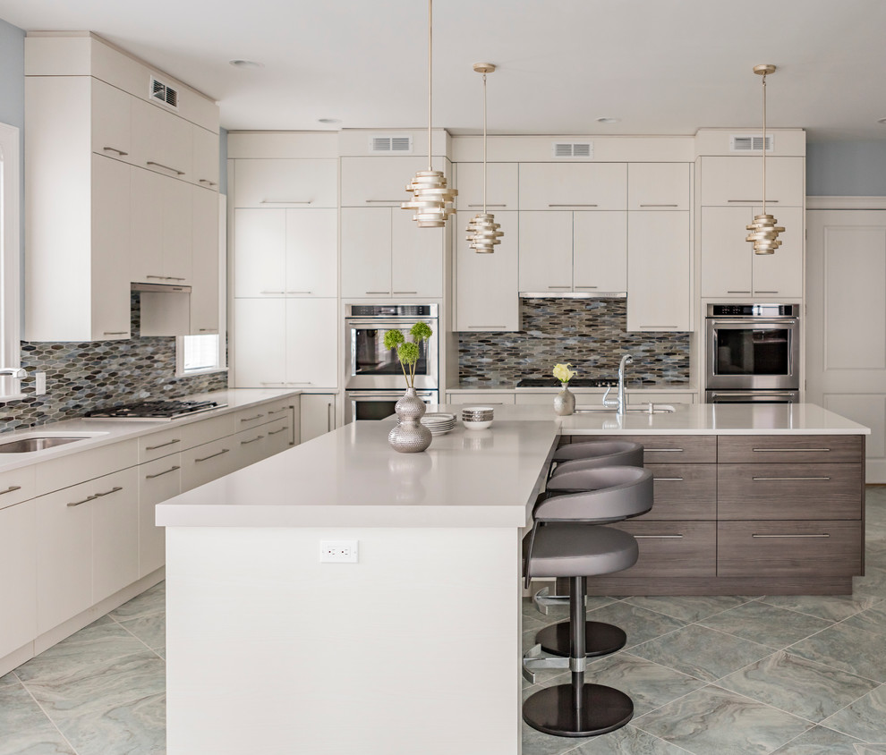 This is an example of a large contemporary l-shaped eat-in kitchen in New York with an undermount sink, flat-panel cabinets, white cabinets, quartz benchtops, multi-coloured splashback, glass tile splashback, panelled appliances, multiple islands and ceramic floors.