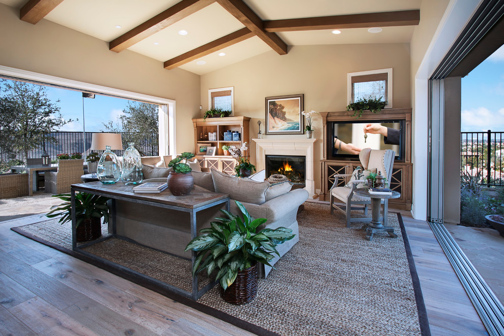 This is an example of a transitional formal living room in Orange County with beige walls, medium hardwood floors, a standard fireplace and a built-in media wall.