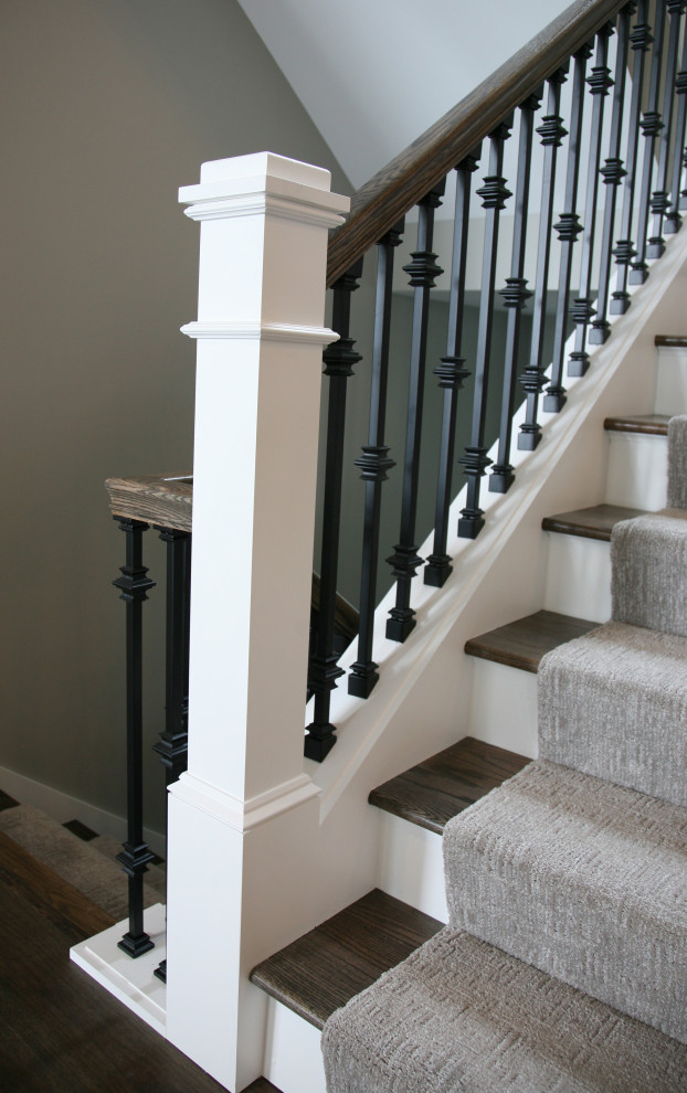 Large elegant wooden u-shaped metal railing staircase photo in Milwaukee with painted risers