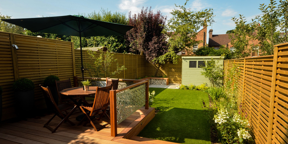 Inspiration for a mid-sized modern backyard partial sun garden for summer in London with decking.