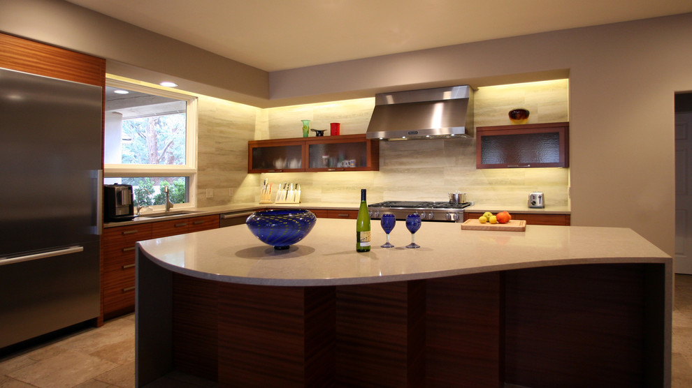 Large contemporary l-shaped eat-in kitchen in Phoenix with a single-bowl sink, flat-panel cabinets, medium wood cabinets, solid surface benchtops, beige splashback, porcelain splashback, limestone floors, with island and stainless steel appliances.