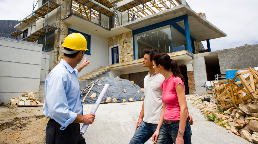 A contractor discussing remodeling plans with a couple in front of a house under construction, symbolizing a stress-free renovation process.
