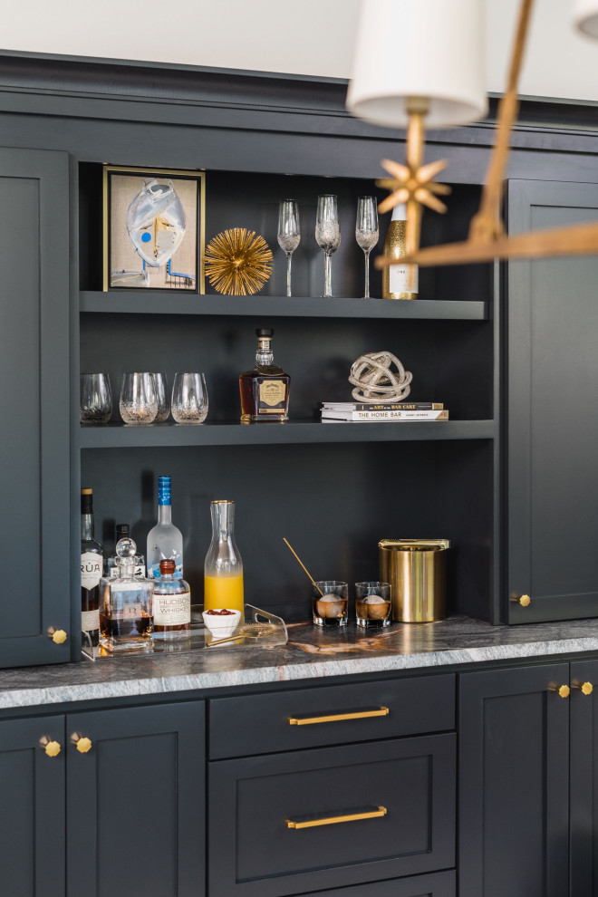 This is an example of a small transitional single-wall home bar in Charlotte with no sink, shaker cabinets, black cabinets, quartzite benchtops, black splashback, timber splashback, medium hardwood floors, brown floor and black benchtop.