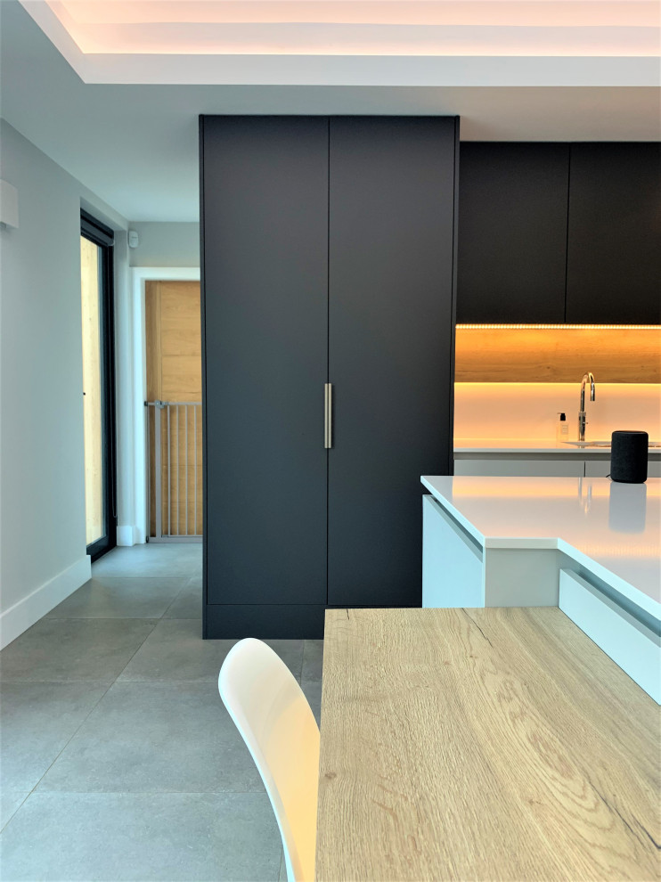 This is an example of a large contemporary l-shaped kitchen/diner in Other with a single-bowl sink, flat-panel cabinets, light wood cabinets, quartz worktops, black appliances, vinyl flooring, an island, grey floors and white worktops.