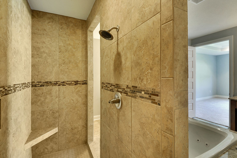 Example of a mid-sized transitional master beige tile and porcelain tile porcelain tile drop-in bathtub design with an undermount sink, raised-panel cabinets, medium tone wood cabinets, granite countertops and gray walls