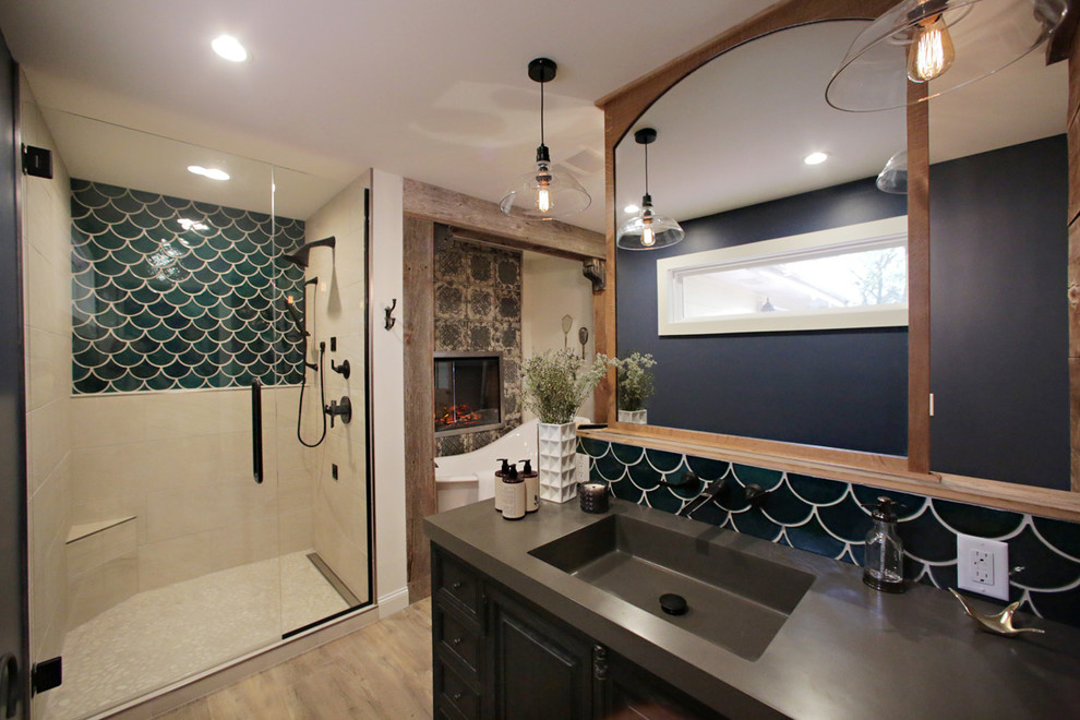 Large country master bathroom in Minneapolis with louvered cabinets, dark wood cabinets, a freestanding tub, an alcove shower, a one-piece toilet, green tile, ceramic tile, blue walls, light hardwood floors, an integrated sink and solid surface benchtops.