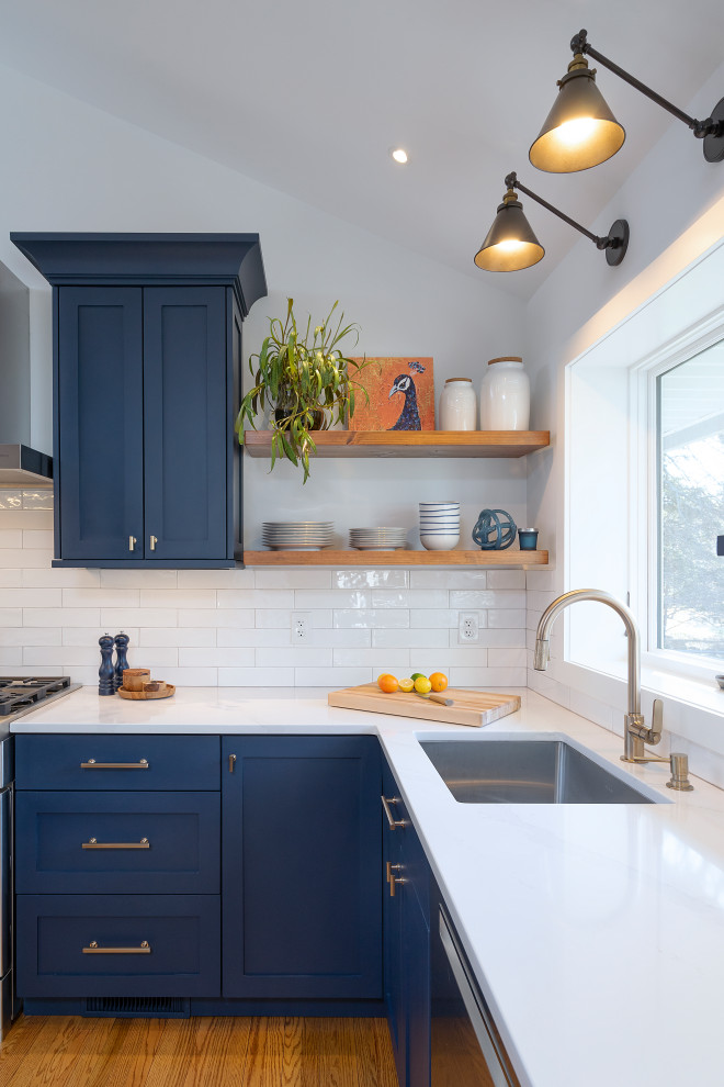This is an example of a transitional l-shaped eat-in kitchen in Philadelphia with a single-bowl sink, shaker cabinets, blue cabinets, quartzite benchtops, white splashback, subway tile splashback, stainless steel appliances, medium hardwood floors, brown floor, white benchtop and vaulted.