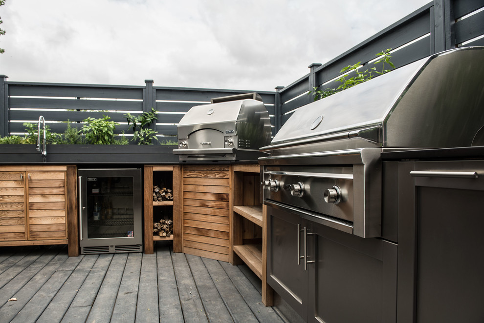 This is an example of a large contemporary backyard deck in Montreal with an outdoor kitchen and no cover.