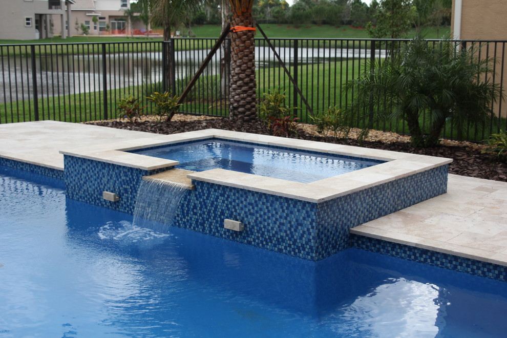 Design ideas for a large tropical backyard rectangular pool in Miami with a hot tub and natural stone pavers.