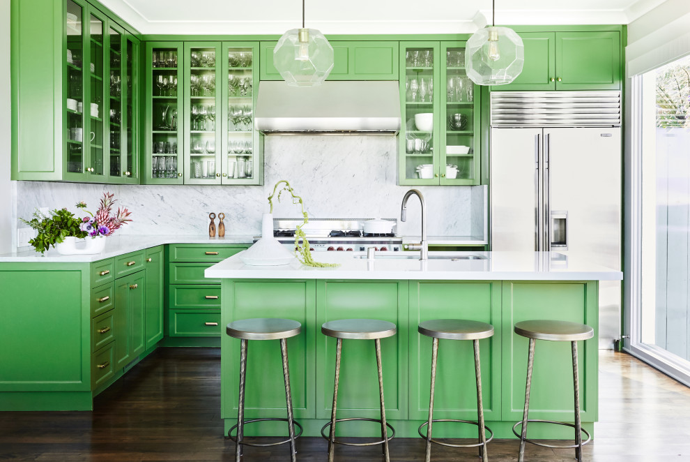 Inspiration for a mid-sized eclectic l-shaped kitchen in San Francisco with an undermount sink, green cabinets, marble benchtops, white splashback, marble splashback, stainless steel appliances, dark hardwood floors, with island, brown floor, white benchtop and glass-front cabinets.