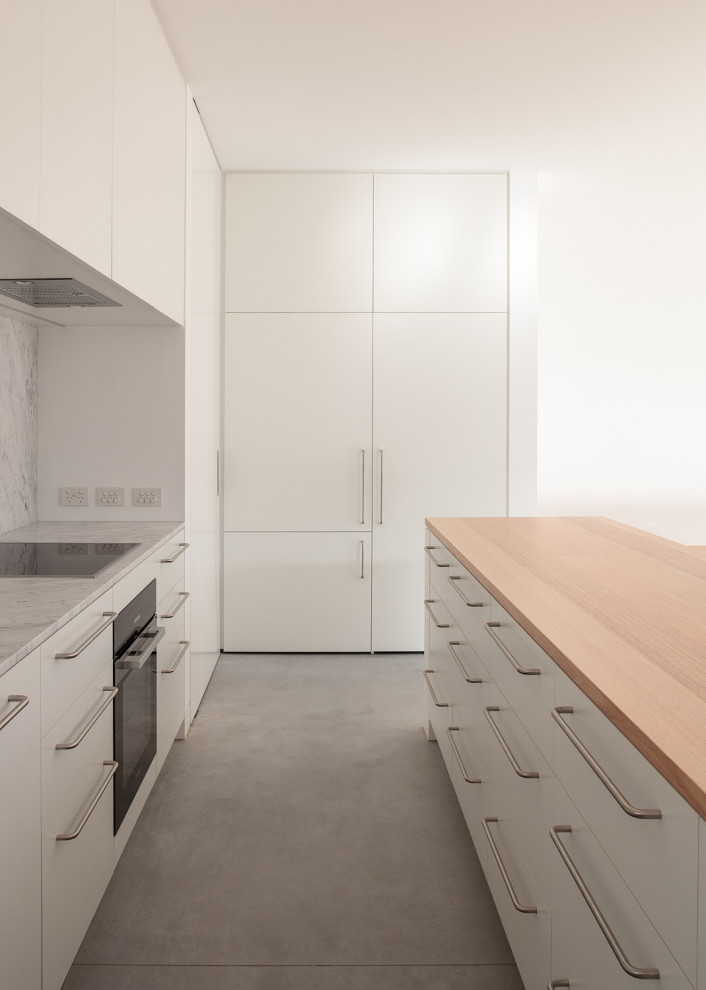 Пример оригинального дизайна: параллельная кухня-гостиная в современном стиле с деревянной столешницей, фартуком из мрамора, бетонным полом и островом