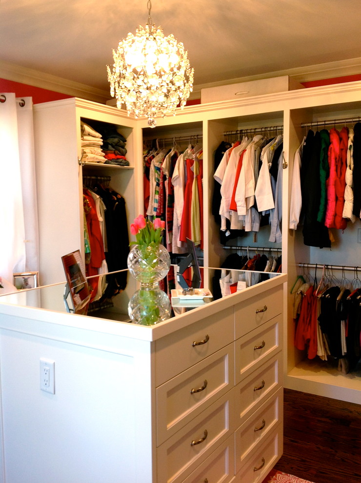This is an example of a mid-sized traditional women's walk-in wardrobe in New York with raised-panel cabinets, white cabinets, dark hardwood floors and brown floor.