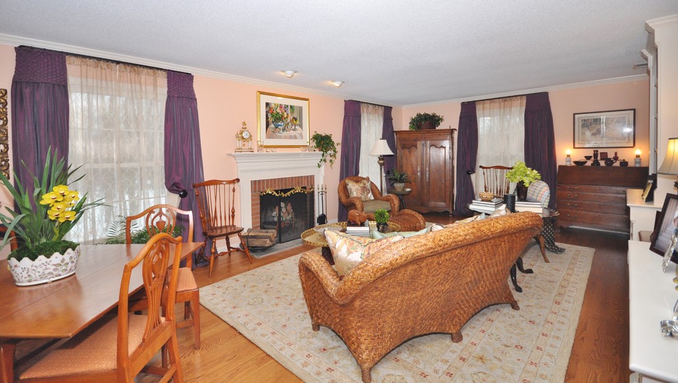 Photo of a mid-sized traditional living room in New York with pink walls, medium hardwood floors, a standard fireplace, a brick fireplace surround and no tv.