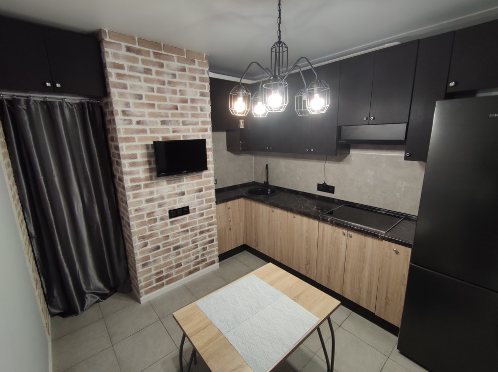 Пример оригинального дизайна: большая угловая кухня в стиле лофт с серым фартуком, полом из керамогранита, серым полом, черной столешницей, телевизором и черными фасадами